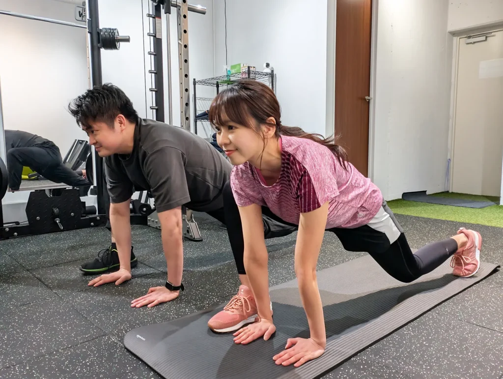 トレーニングの前に無料ダイナミックストレッチをやっているトレーナーとお客様