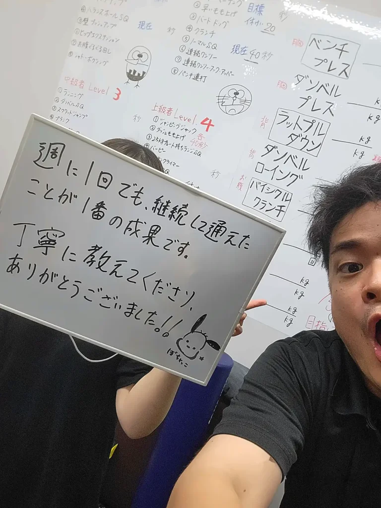 週1回のパーソナルトレーニングを継続し、成果を実感した利用者が感謝のメッセージボードを持つ様子